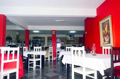 a dining room with white tables and red walls at Hotel Miramar Fogo Brava in São Filipe