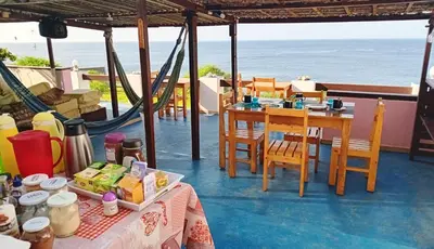 a room with a table and chairs and the ocean at Pousada Villa Concetta AC in Cidade Velha
