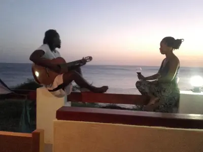 two people sitting on a ledge playing a guitar at Pousada Villa Concetta AC in Cidade Velha