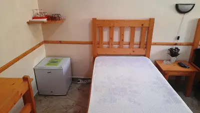 a small room with a bed and a small refrigerator at Pousada Villa Concetta AC in Cidade Velha