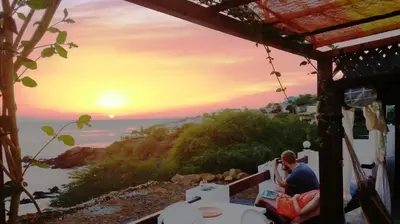 a man sitting on a porch watching the sunset at Pousada Villa Concetta AC in Cidade Velha
