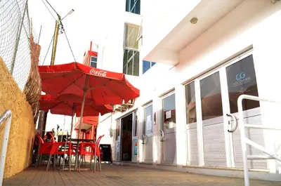 a table with red chairs and an umbrella outside a building at Apartamento Rita in Praia