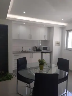a kitchen with a glass table and chairs at Apto T1 Comfort in Praia