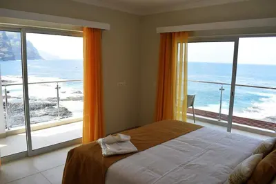 a bedroom with a bed with a view of the ocean at Tiduca Hotel in Ponta do Sol
