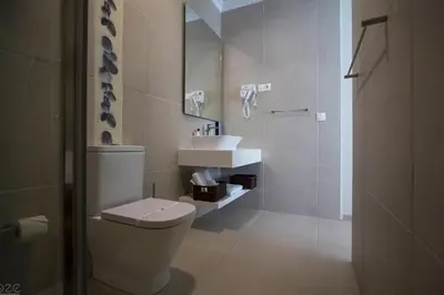 a white bathroom with a toilet and a sink at Tiduca Hotel in Ponta do Sol