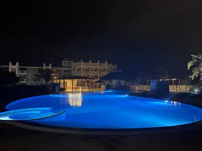a large blue swimming pool at night at Apartment | in Tropical Resort | pool | close to beach in Santa Maria