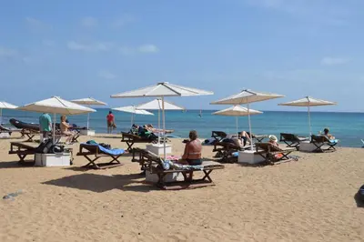a group of people sitting on a beach with umbrellas at Apartment | in Tropical Resort | pool | close to beach in Santa Maria