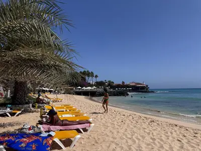 a beach with lounge chairs and people on the beach at Apartment | in Tropical Resort | pool | close to beach in Santa Maria