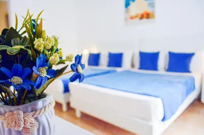 a bedroom with a bed with blue pillows and a vase of flowers at Aparthotel Santa Maria Beach in Santa Maria