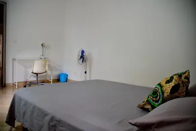 a bedroom with a bed with a phone and a chair at Meeting Point Hostels-Tarrafal Center, also in Praia & Fogo-NO CASH ACCEPTED in Tarrafal