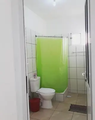 a bathroom with a green shower curtain and a toilet at Meeting Point Hostels-Tarrafal Center, also in Praia & Fogo-NO CASH ACCEPTED in Tarrafal