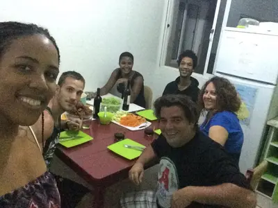 a group of people sitting around a table eating pizza at Meeting Point Hostels-Tarrafal Center, also in Praia & Fogo-NO CASH ACCEPTED in Tarrafal