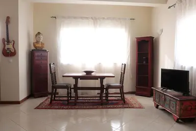 a dining room with a table and chairs and a television at Bouganville in Mindelo