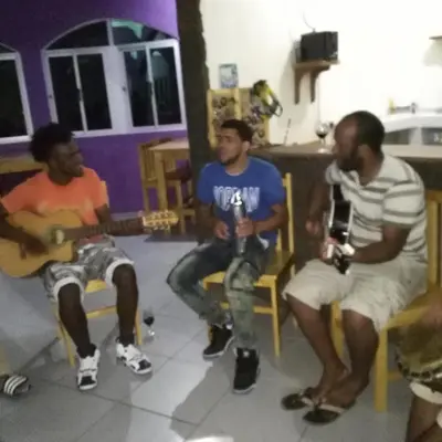a group of three men sitting in chairs playing guitar at casa alcindo in Portela