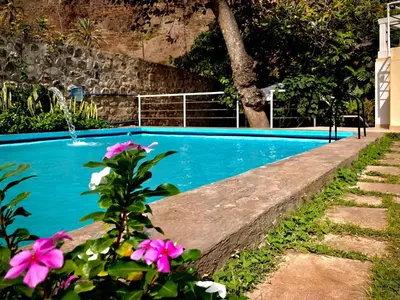 a swimming pool with pink flowers in front of it at Casa Santa Barbara Deluxe in Ribeira Grande