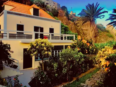 a white house on a hill with trees and bushes at Casa Santa Barbara Deluxe in Ribeira Grande