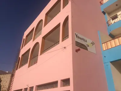 a pink building with a sign on the side of it at Vannilla Residencial in Mindelo