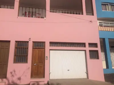 a pink house with two garage doors and windows at Vannilla Residencial in Mindelo