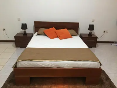 a bed with two orange pillows on it in a bedroom at Vannilla Residencial in Mindelo