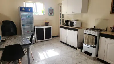 a kitchen with white appliances and a table in it at Meeting Point Hostels-Praia Beachwalk-NO CASH ACCEPTED-Also in Fogo & Tarrafal in Praia
