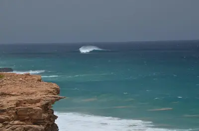 a wave in the ocean next to a cliff at Barracudamaio in Morro