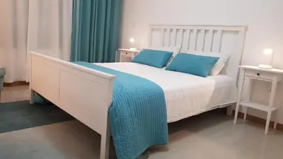 a white bed with blue pillows in a bedroom at Elegant Modern Apartment with AirCond in Praia
