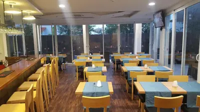 a restaurant with tables and yellow chairs and windows at Blue Marlin Hotel in Mindelo