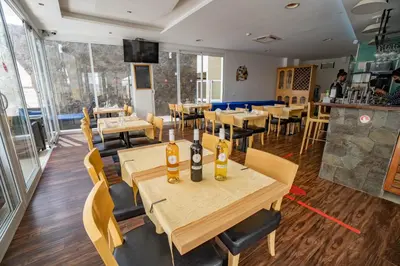 a restaurant with wooden tables and chairs and a bar at Blue Marlin Hotel in Mindelo