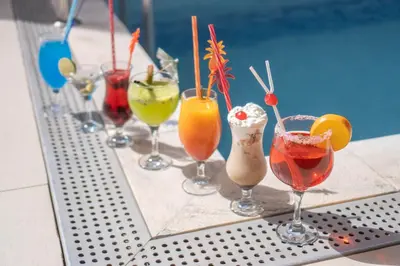 a group of different cocktails sitting on a table next to a pool at Blue Marlin Hotel in Mindelo