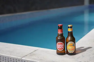 two bottles of beer sitting next to a swimming pool at Blue Marlin Hotel in Mindelo