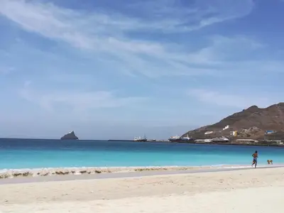a person walking on a beach with a dog at Private Apartament Celestina & Carlos in Mindelo
