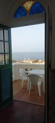 a room with a table and chairs and a view of the ocean at Hotel Savana in São Filipe