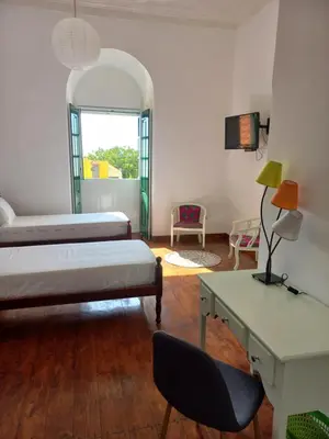 a room with two beds and a table and a desk at Hotel Savana in São Filipe