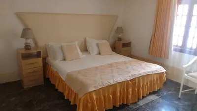 a bedroom with a bed and two night stands and a window at Residencial Cabo Verde Palace in Santa Maria
