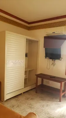 a room with a closet with a television and a table at Residencial Cabo Verde Palace in Santa Maria
