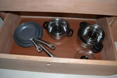 a wooden drawer with utensils and pots and pans at Studio M in Mindelo