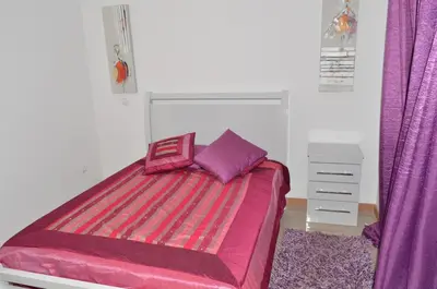 a bedroom with a pink bed with purple sheets at House Gonçalves in Praia