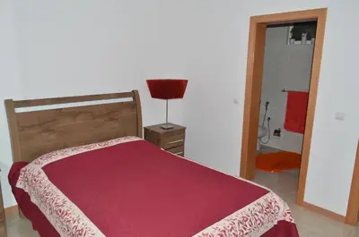 a bedroom with a bed with a red blanket and a lamp at House Gonçalves in Praia