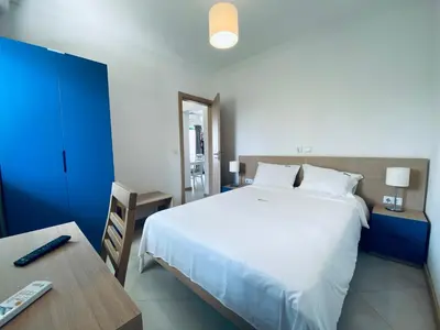 a bedroom with a large white bed and a table at ApartHotel NhaTerra in Santa Maria