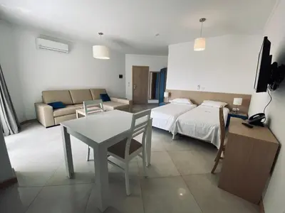 a room with a bed and a table and a couch at ApartHotel NhaTerra in Santa Maria
