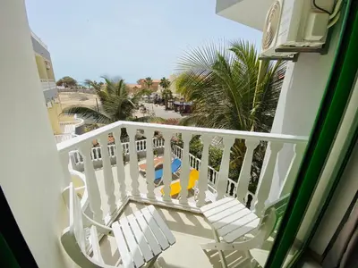 a balcony with a view of the beach and palm trees at ApartHotel NhaTerra in Santa Maria