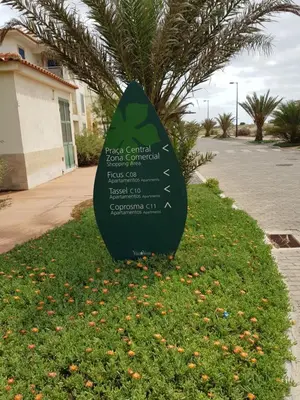 a surfboard sign in the grass near a street at Surf Beach Vila Verde apartments in Santa Maria