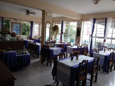 a restaurant with blue tables and chairs and windows at Pensao Mille Nuits in Tarrafal