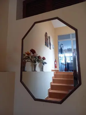 a mirror hanging on a wall with stairs and flowers at Pensao Mille Nuits in Tarrafal