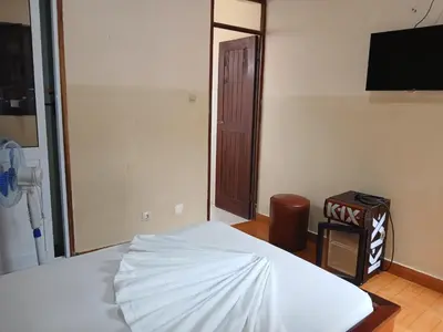 a bedroom with a white bed and a television at Pensao Mille Nuits in Tarrafal