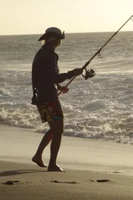 a woman standing on the beach holding a fishing pole at A Caminhada in Morro