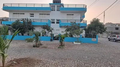 a blue and white building with trees in front of it at Casa Mendes in Tarrafal