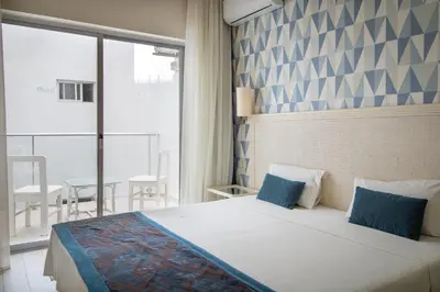 a bedroom with a large bed with blue pillows at Ouril Hotel Agueda in Sal Rei