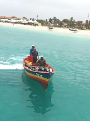 three people on a boat in the water near a beach at Salzen Portas de Sol in Santa Maria