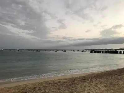 a beach with boats in the water and a pier at Salzen Portas de Sol in Santa Maria